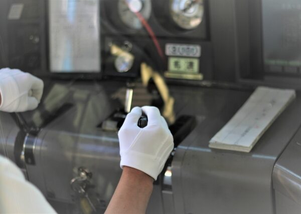 Train conductor operating controls with precision and care in white gloves