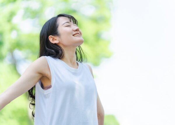 リフレッシュする女性が深呼吸をしている公園の様子