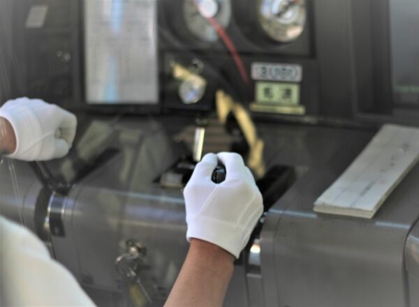 Train conductor operating controls with precision and care in white gloves